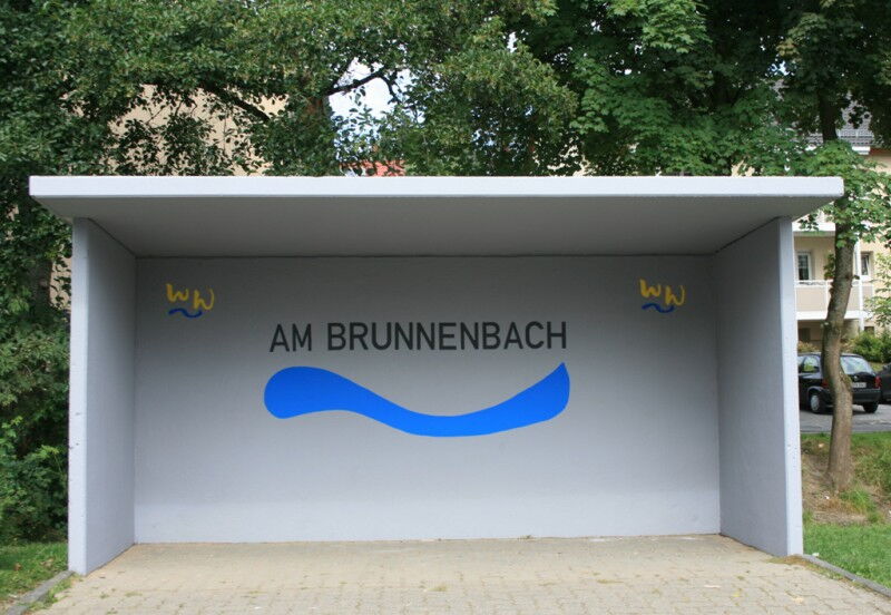 Buswartehäuschen mit Brunnenbach- und Wogeemblem